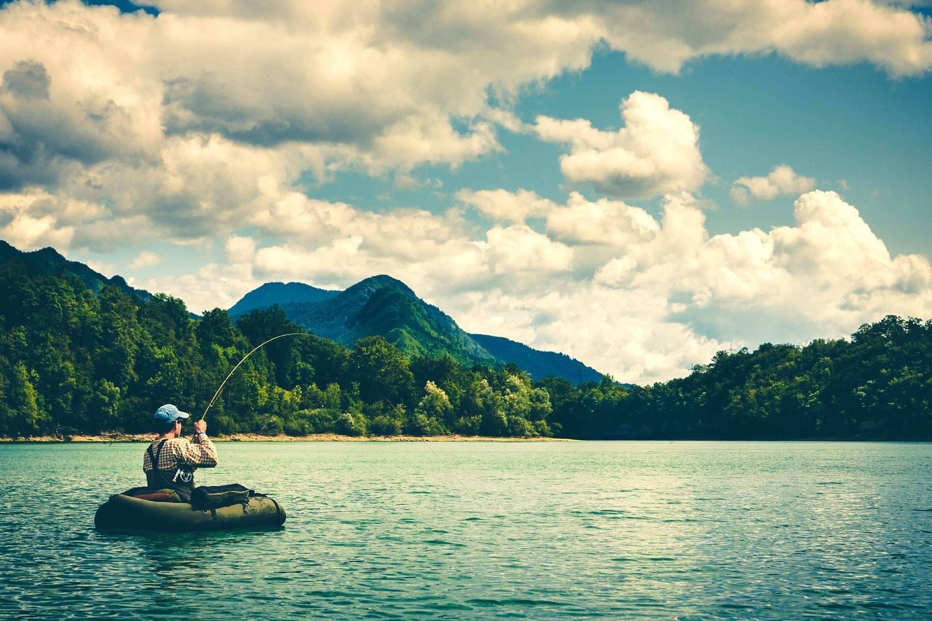 Angler fishing from a float tube in a scenic lake, perfect for Bass Fly Fishing Bug enthusiasts