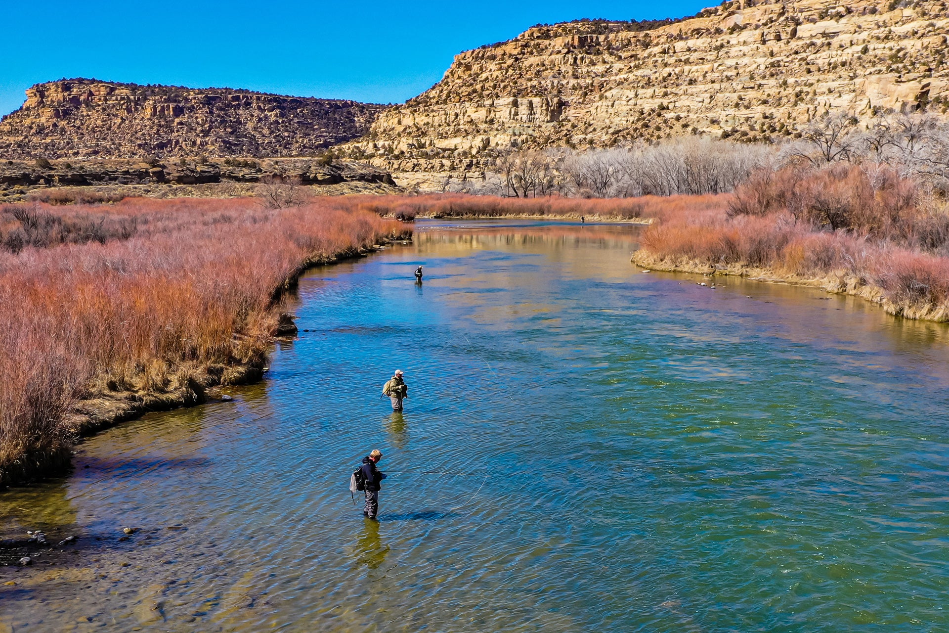 Fly fishing tools and nippers in a scenic river setting with anglers casting lines