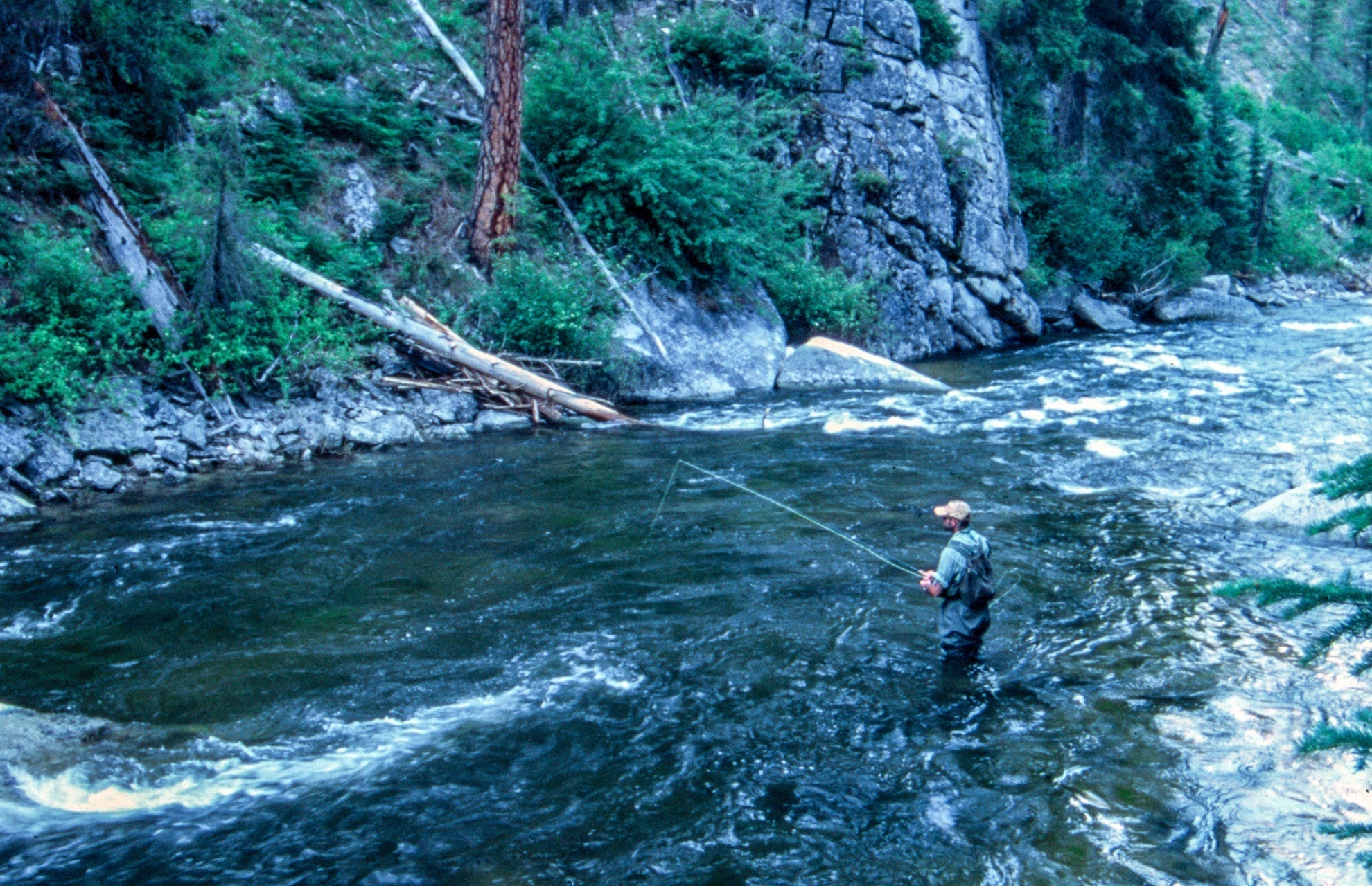 Angler casting in a river while using jig egg wet flies for trout fishing