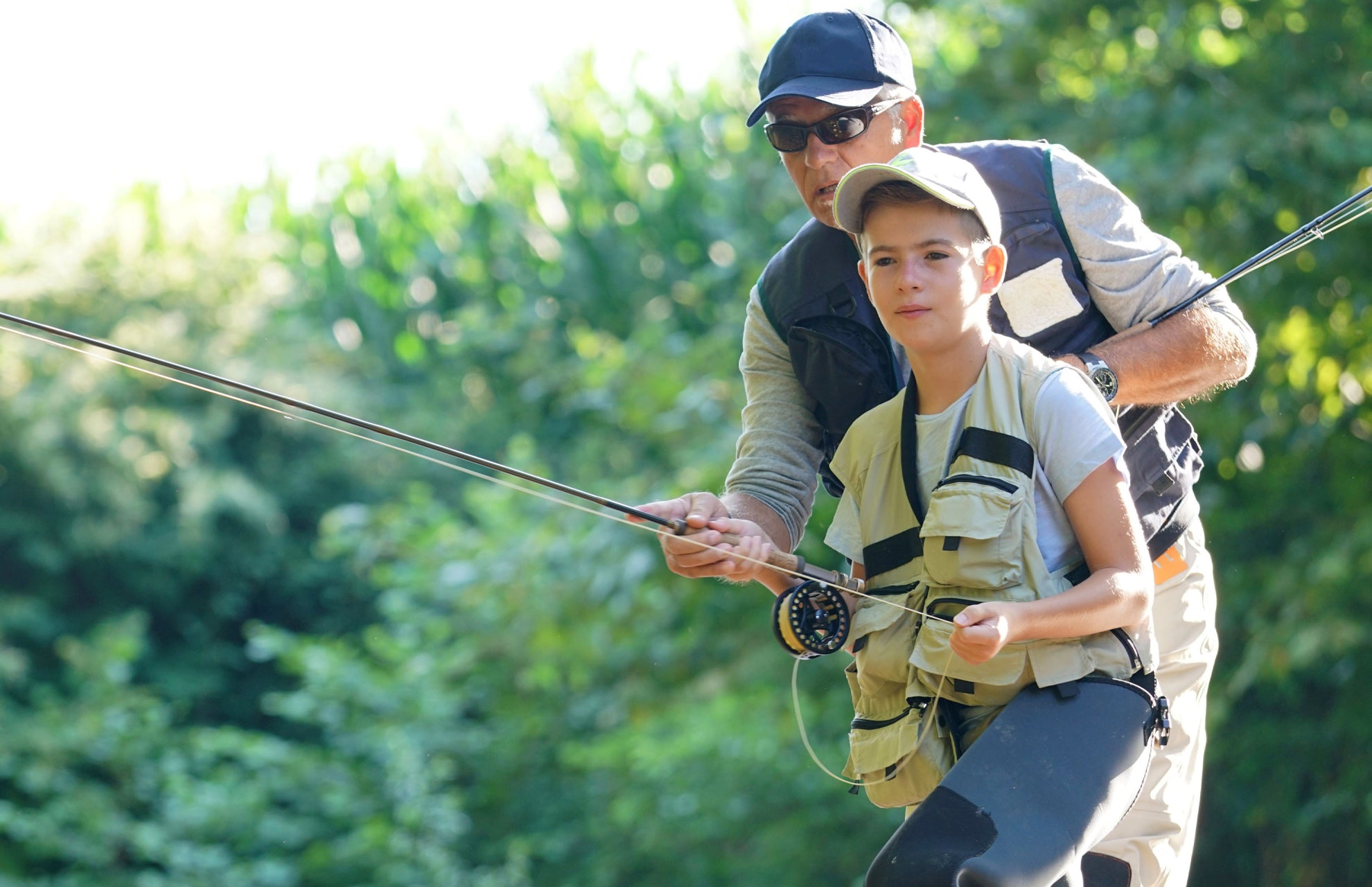 A man guiding a child in fly fishing using san juan power worm wet flies in a natural setting