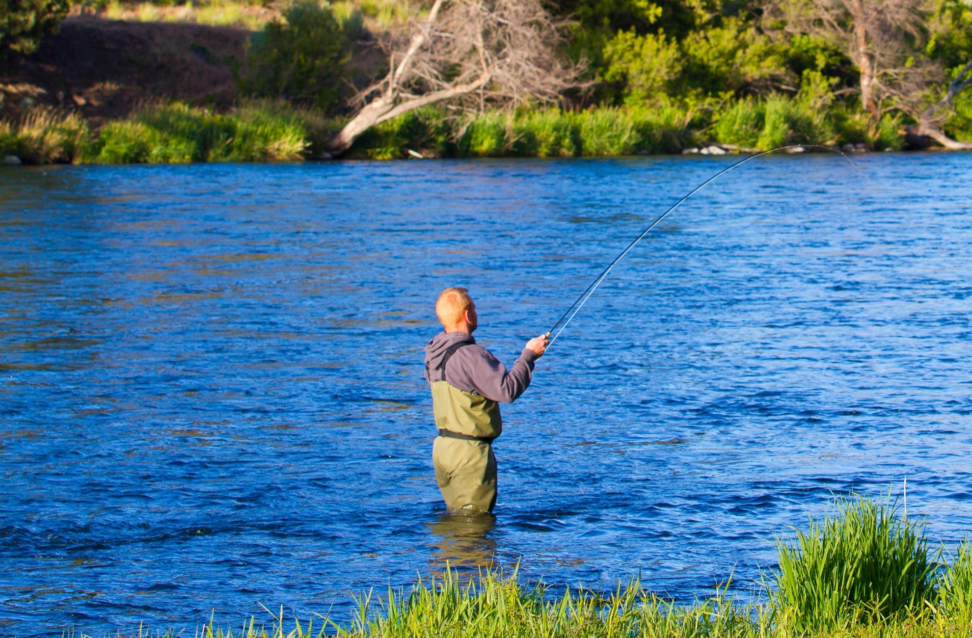 Angler casting a line in a river while using Pat's Rubber Legs Nymph for trout fishing